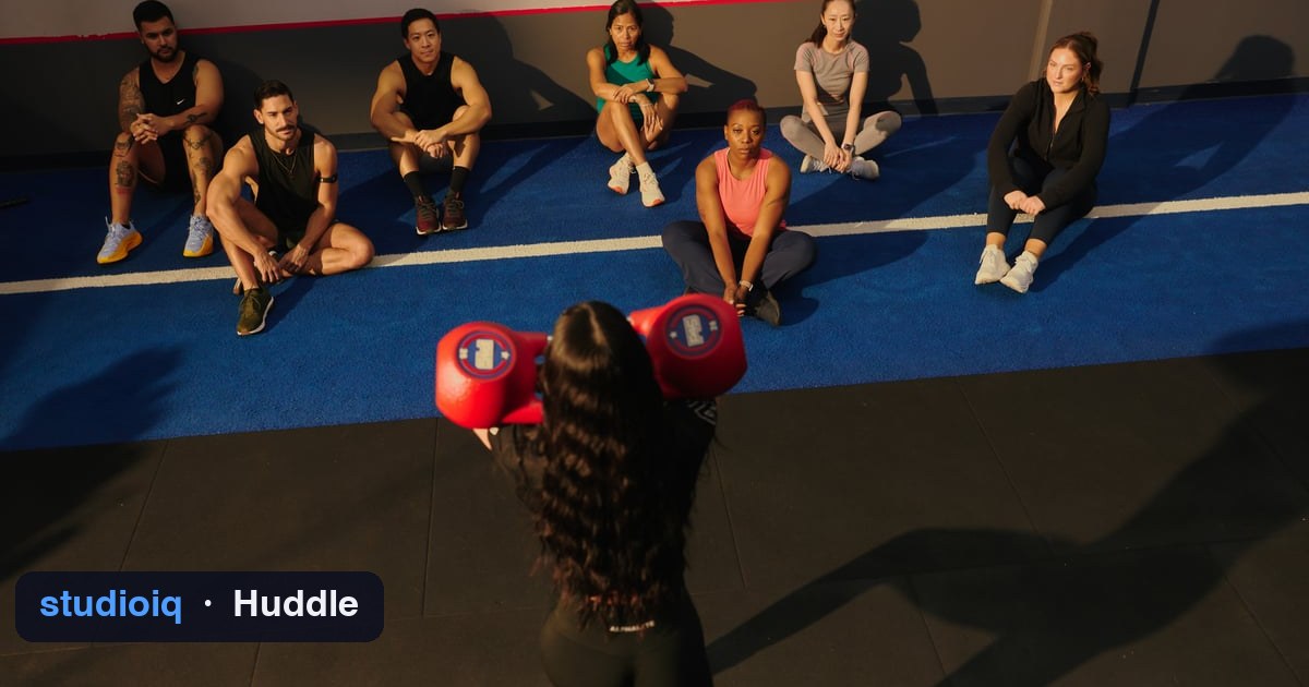 A coach leading the pre-class huddle with the class seated in a semicircle